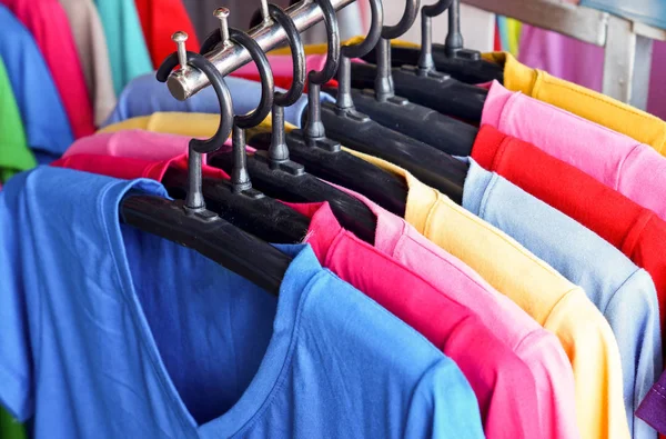 row of bright t-shirts on hangers