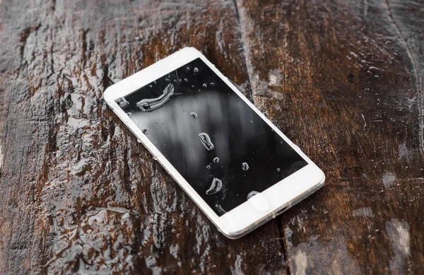 木地板上的湿式智能手机 — 图库照片