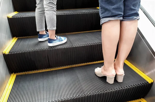 Mor och en ung kvinnlig unge på en glidande rulltrappa — Stockfoto