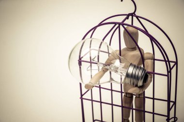 Ahşap şekil manken bir ampulü taşıyan bir kafes içinde