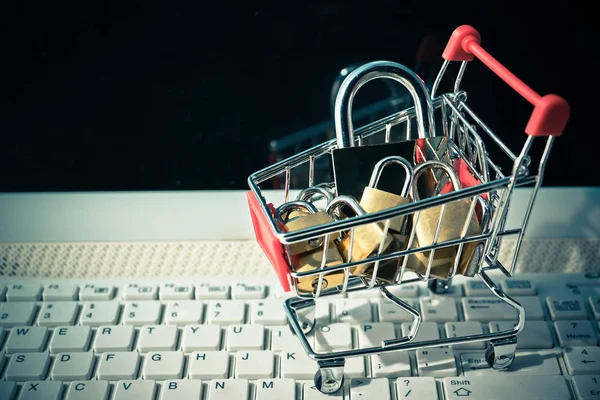 A trolley on computer keyboard with padlocks — Stock Photo, Image