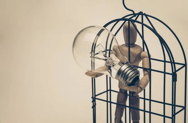 Madeira Figura Manequim em uma gaiola carregando uma lâmpada incandescente — Fotografia de Stock
