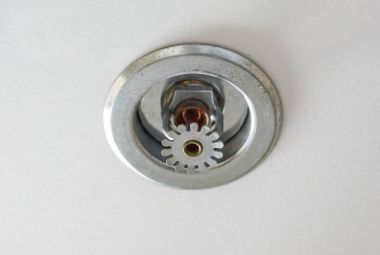 Yangın dedektörü ve arka plan olarak gri tavan ile söndürme