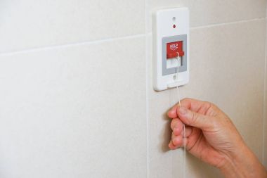 Yaşlı hasta tuvalette acil yardım çağrısı kırmızı anahtar çekerek