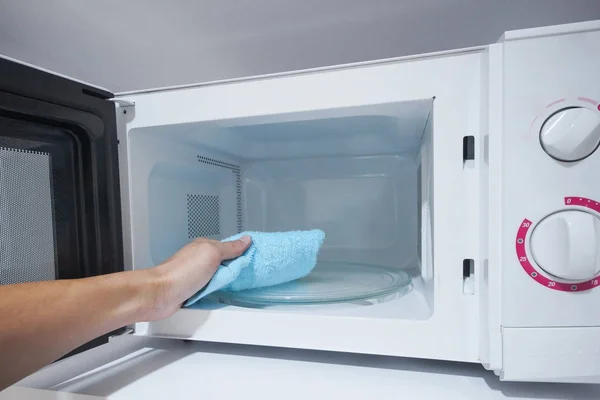 Using a cloth to clean a microwave oven