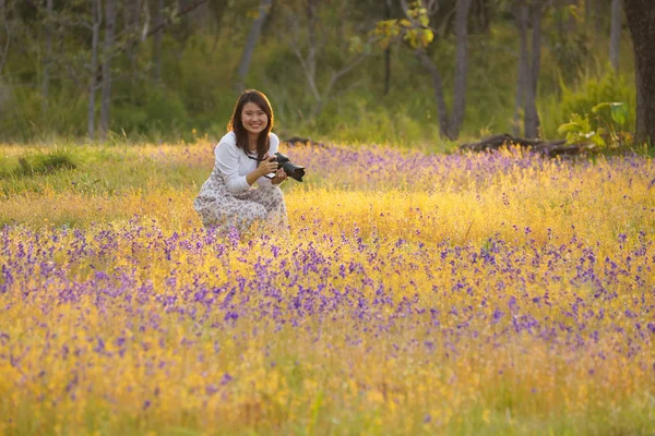 A girl with a camera in a beautiful grass flower field at Soi Sawan waterfall, Ubon Ratchathani, Thailand