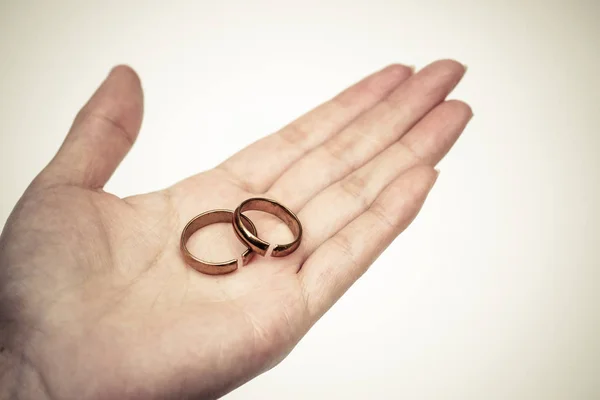 Hand holding broken rings / Divorce and ending relationship concept