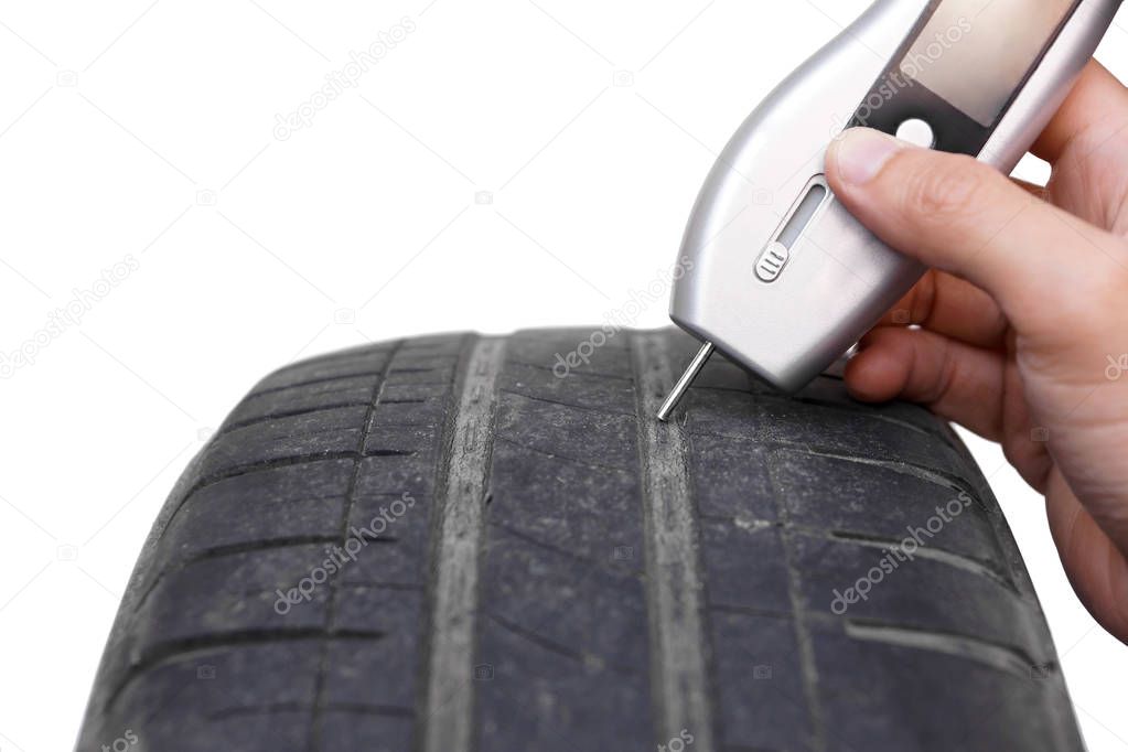 Using a digital tire tread depth measuring tool with old tire isolated on white / Road safety and risks of using old tire concept