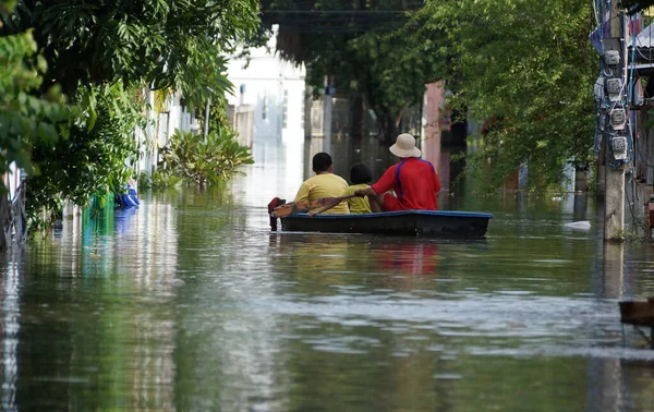 People rowing a boat through a flooded street in Thailand