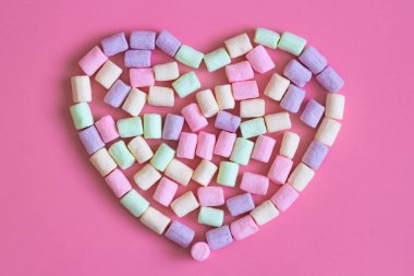 Pembe arka planda izole edilmiş renkli mini marşmelovlar. Yumuşak marşmelov dokusu ve desen sevgililer günü için kalp olarak.