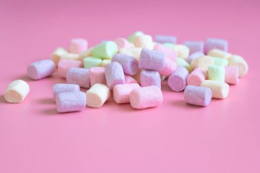 Pembe arka planda renkli marşmelovlar, makro. Yumuşak marşmelov dokusu pastel renklerle kaplanır.
