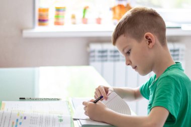 Uzaktan öğrenme çevrimiçi eğitim. Öğrenci evde ders çalışıyor ve ev ödevi yapıyor. Antrenman kitaplarıyla oturan.