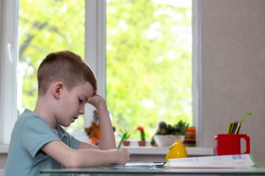 Uzaktan öğrenme çevrimiçi eğitim. Öğrenci evde ders çalışıyor ve ev ödevi yapıyor. Antrenman kitaplarıyla oturan.