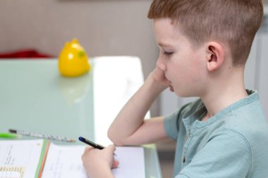 Uzaktan öğrenme çevrimiçi eğitim. Öğrenci evde ders çalışıyor ve ev ödevi yapıyor. Antrenman kitaplarıyla oturan.