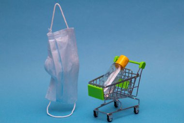 Alışveriş arabasında antiseptik var. Uçan tıbbi maske. Covid-19 salgını sırasında koruma kiti. Alışveriş arabası çevrimiçi alışveriş.