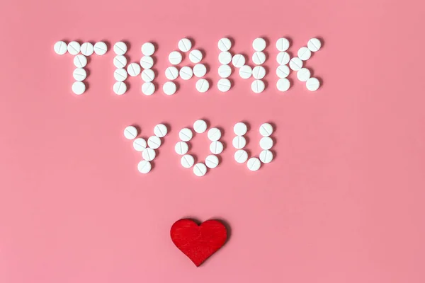 Internationals nurses day, week concept, Text Thank you by tablets and red heart on pink background.