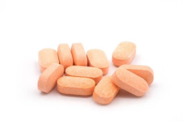 Mucchio di pillole arancioni di vitamine su sfondo bianco — Foto Stock