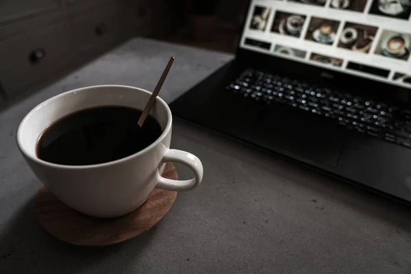 Coffee on concrete table with laptop as backdrop.