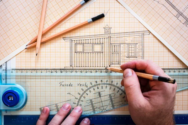 Hands drawing cabin on drawing board with ruler and pencils. Designer, architect, draw, lines, paper, work, working, at work concept.