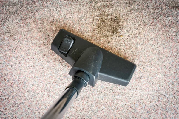 Vacuum cleaner head and dust particles on the carpet floor. Household and cleaning concept.