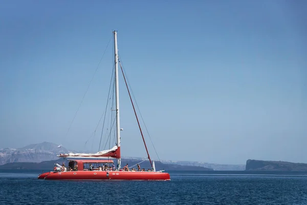 Red sailboat on the ocean in Santorini/Greece. Marine, transport, boating, sailing, ship, yacht, travel, explore, cruise concept.