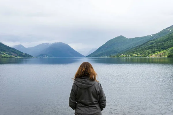 Girl looking towards the sea and the beautoful fjords of Norway. Road trip, travel, scenery, model, freedom, epic concept.