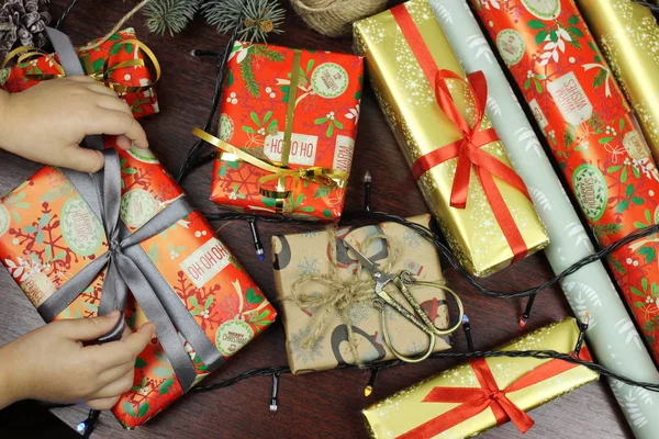 Bambina impacchi regali di Natale in carta colorata sul tavolo. tradizioni familiari . — Foto Stock