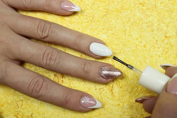 Women\'s hands make nail Polish on a yellow background. Beauty, the concept of the manicure