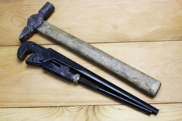 Werkzeuge von oben isoliert auf Holzhintergrund. Rohrschlüssel und Hammer — Stockfoto