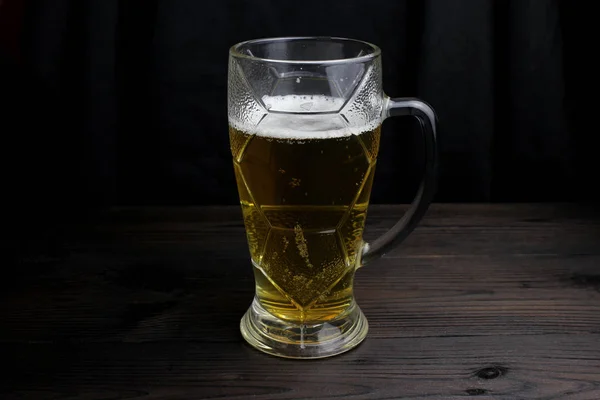 Un vaso de cerveza sobre un fondo oscuro sobre una mesa de madera — Foto de Stock