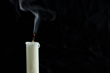 Siyah arka planda dumanı olan sönmüş bir mum. Metnin için boşluk kopyala