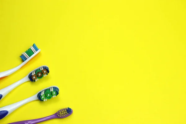 Four toothbrushes on a yellow background — Stock Photo, Image