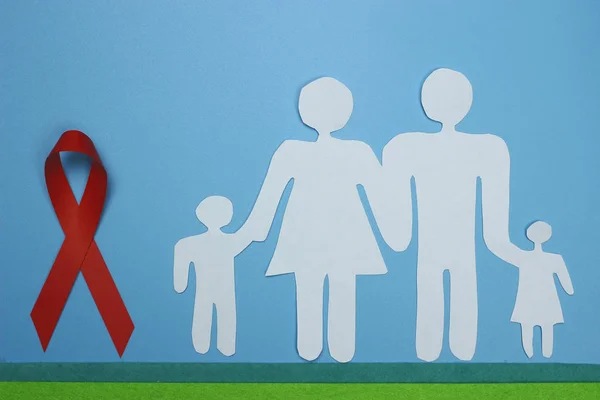 Červená stuha a papírová silueta rodiny. Symbol povědomí o AIDS — Stock fotografie