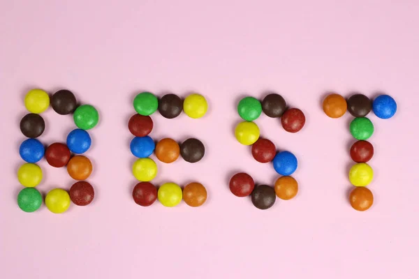 Le mot Meilleur de bonbons colorés sur un fond rose — Photo