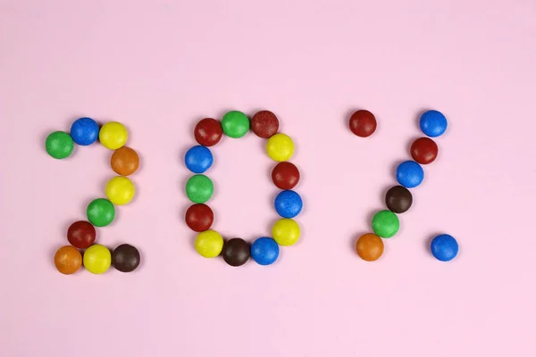 Venti per cento di caramelle colorate su uno sfondo rosa — Foto Stock