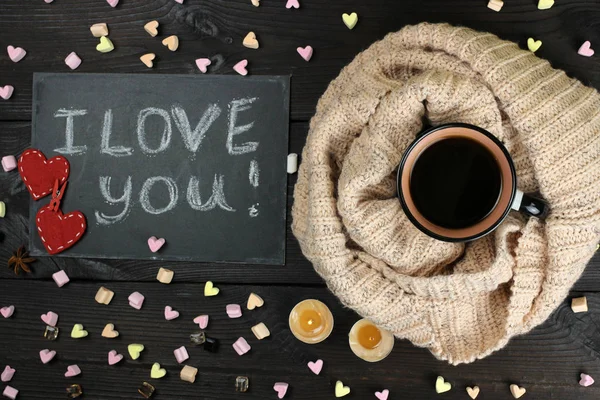 A Cup of tea and hearts on a wooden background. The inscription I love you in chalk on the Board. The view from the top — Stock Photo, Image