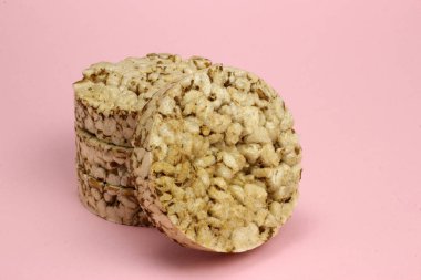 Pembe arka planda bir yığın pirinç ve karabuğday ekmeği. Diyet, düzgün beslenme, vegan.