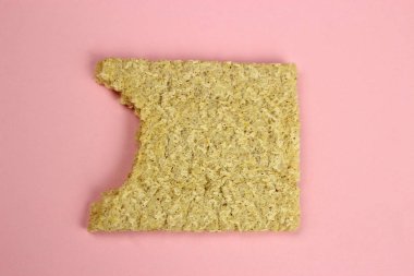 Pembe arka planda Crispbread 'i ısırmış. Diyet, düzgün beslenme, vegan.