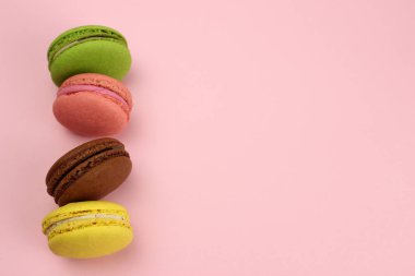 Pembe arkaplandaki renkli badem kurabiyeleri ya da badem kurabiyeleri, metin alanınızı kopyalayın