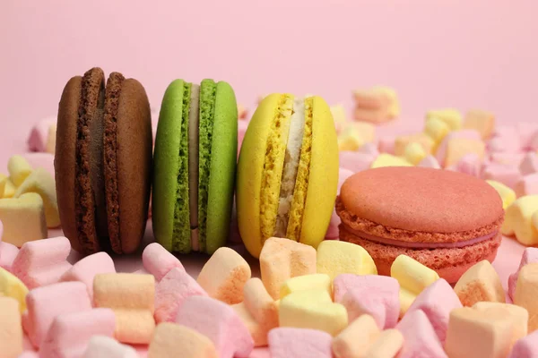 Colored macaroons or macarons, marshmallow hearts on a pink background