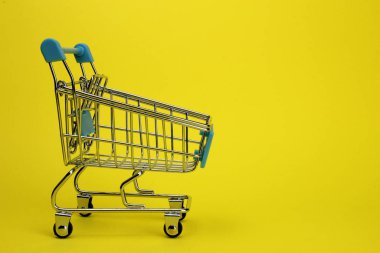 Mini supermarket cart, trolley on a yellow background. Purchases