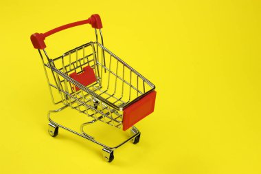 Mini supermarket cart, trolley on a yellow background. Purchases