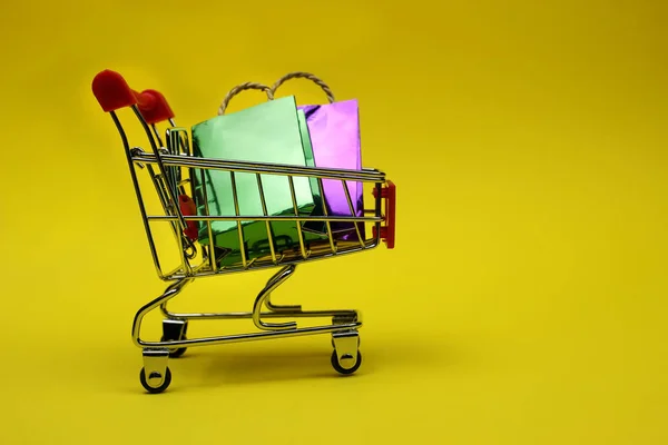 Sacos de compras coloridos e um carrinho de supermercado, carrinho. Vício em compras, amante de compras ou conceito shopaholic — Fotografia de Stock