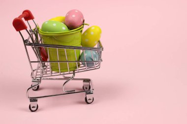 Alışveriş arabasında Paskalya yumurtası, pembe arka planda tramvay.