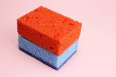 Bulaşıklar için mavi ve kırmızı sünger ya da pembe arka planda temizlik