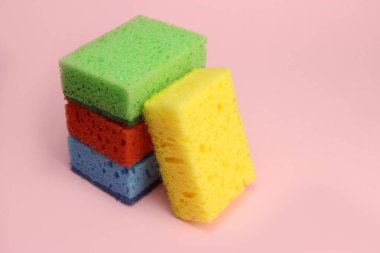 Bulaşıklar için renkli süngerler ya da pembe arka planda ev temizliği