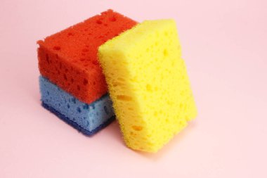 Bulaşıklar için renkli süngerler ya da pembe arka planda ev temizliği