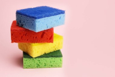Bulaşıklar için renkli süngerler ya da pembe arka planda ev temizliği
