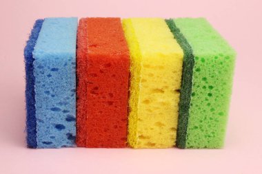 Bulaşıklar için renkli süngerler ya da pembe arka planda ev temizliği