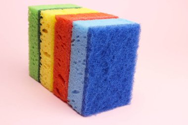 Bulaşıklar için renkli süngerler ya da pembe arka planda ev temizliği